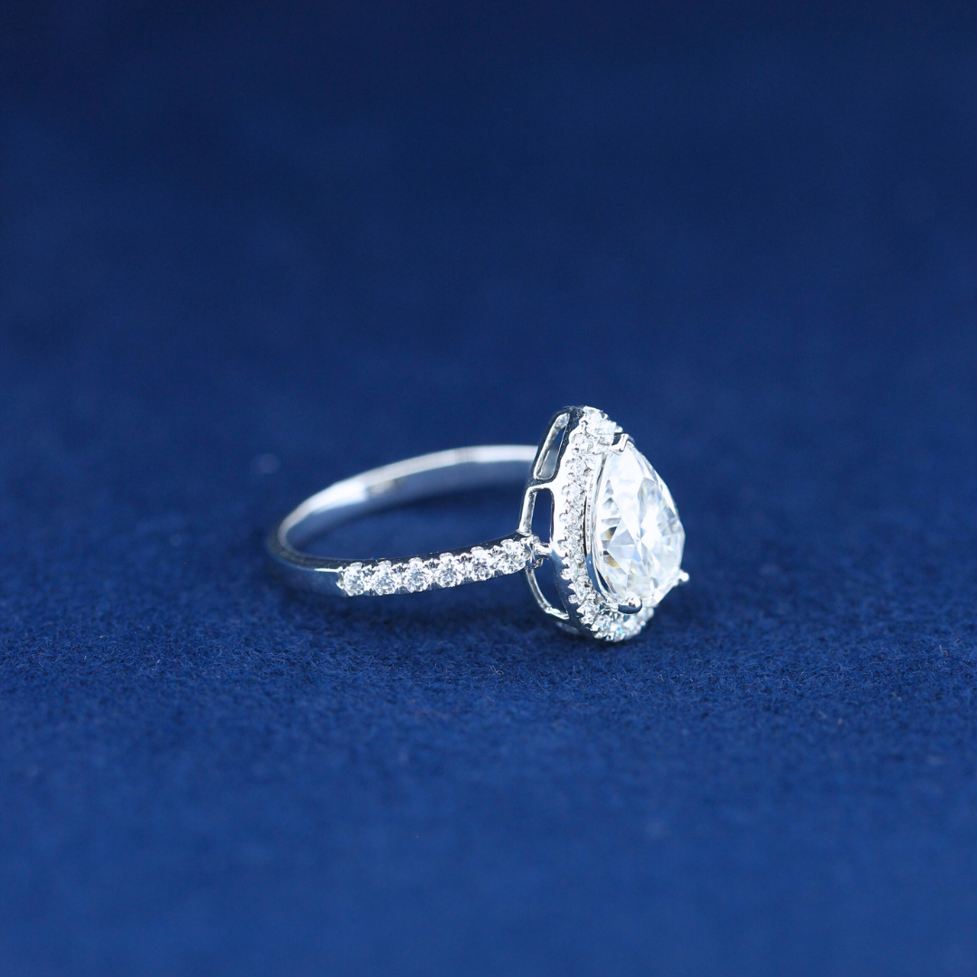 A left-side view of a fine jewelry hip-hop pear moissanite diamond ring in 925 sterling silver, highlighting the intricate prong setting and shimmering diamond.