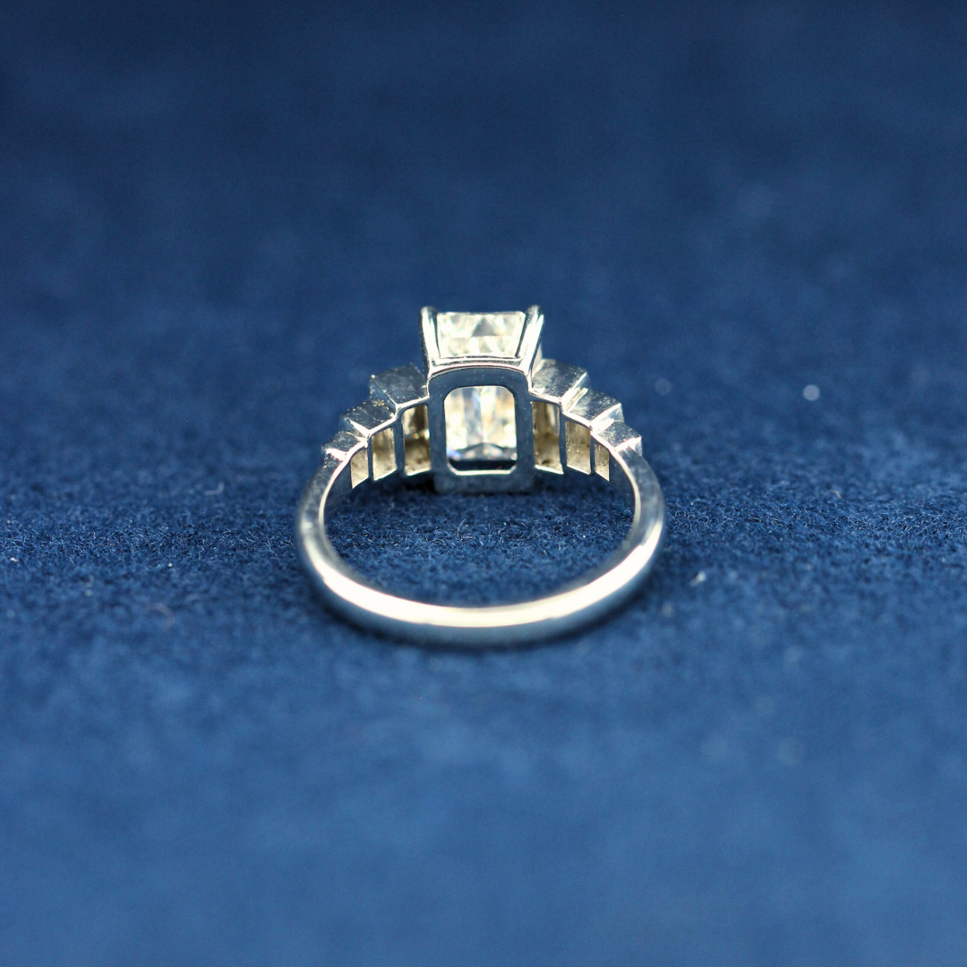 A back-side view of a fine jewelry emerald-cut moissanite diamond ring in 925 sterling silver, displaying the polished band and delicate craftsmanship.