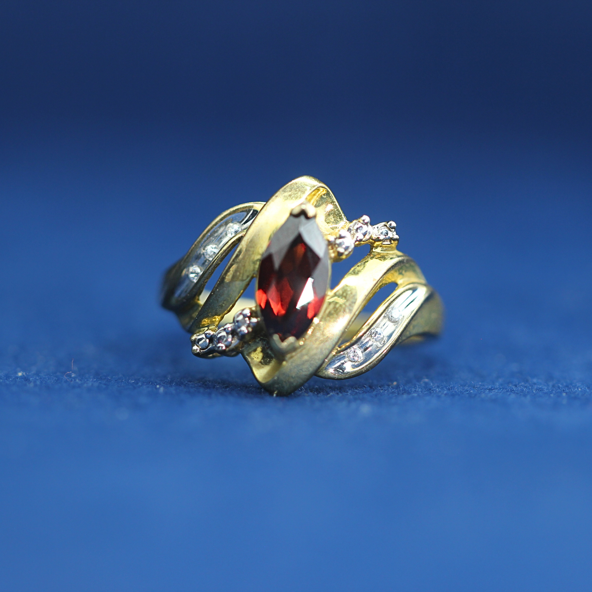 Front view of preowned garnet gold ring crafted in 14K silver with moissanite diamonds – luxury vintage style that pairs with half iced out custom jewelry