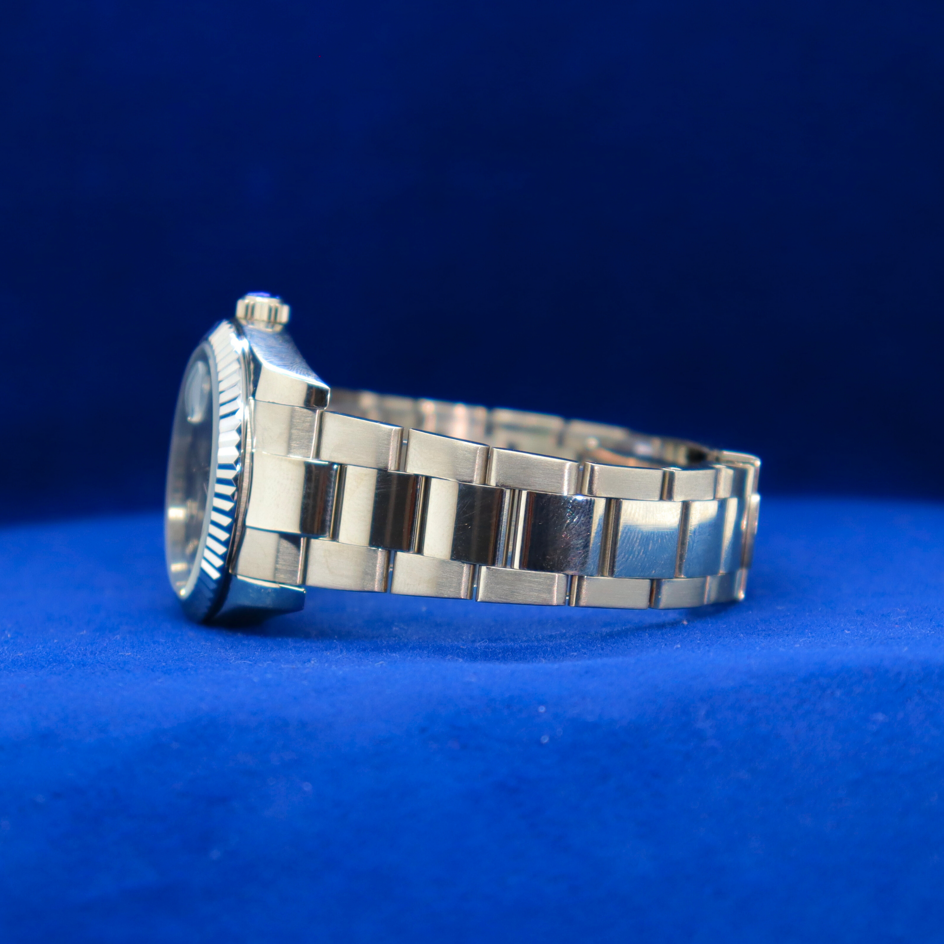 Left side view of luxury sunburst blue dial watch, half iced out custom style with bold shimmering details