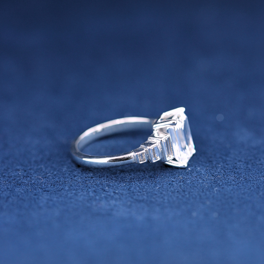 A right-side view of a fine jewelry emerald-cut moissanite diamond ring in 925 sterling silver, highlighting the intricate setting and shimmering moissanite diamonds.